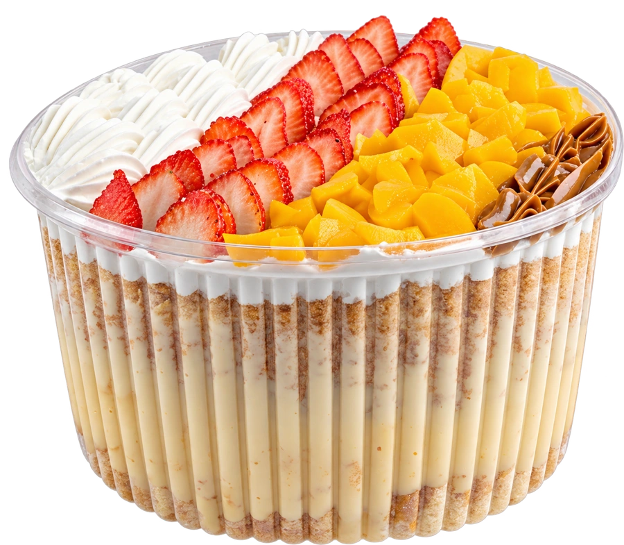 Tres leches con frutillas, durazno, crema y manjar en recipiente transparente
